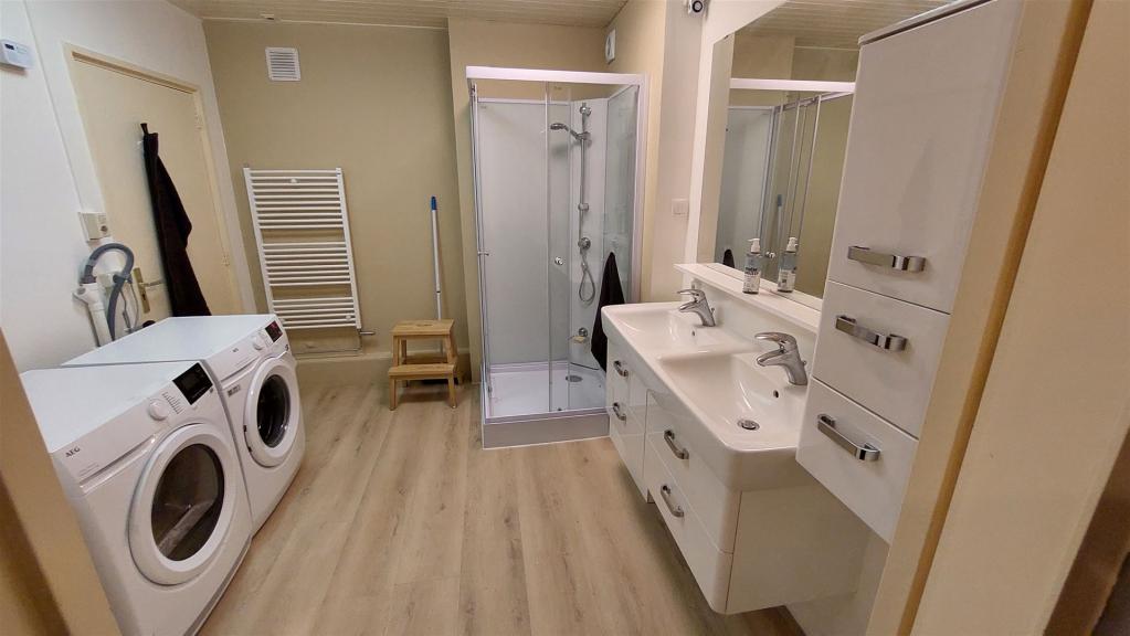De gedeelde badkamer (nieuw 2024), douchecabine, dubbele wastafel, grote spiegel, handdoekradiator, nieuwe wasmachine en nieuwe wasdroger.